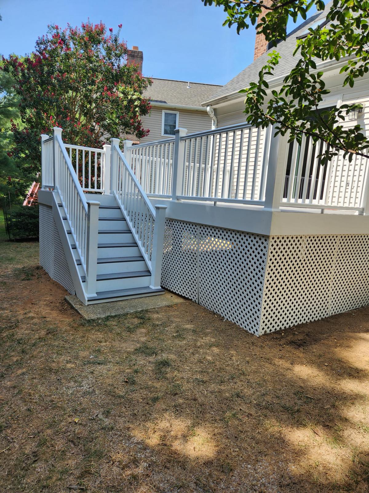 A finished deck with white railing and lattice skirting built by Skip's Modern Carpentry